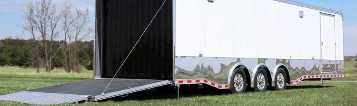 The opened back of a Haulmark trailer that's parked in a grass field